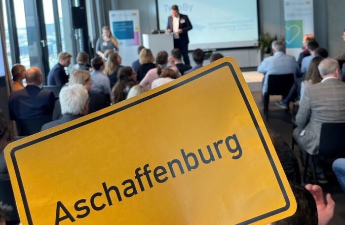 Auftaktveranstaltung TwinBy - Schild Aschaffenburg wird hochgehalten