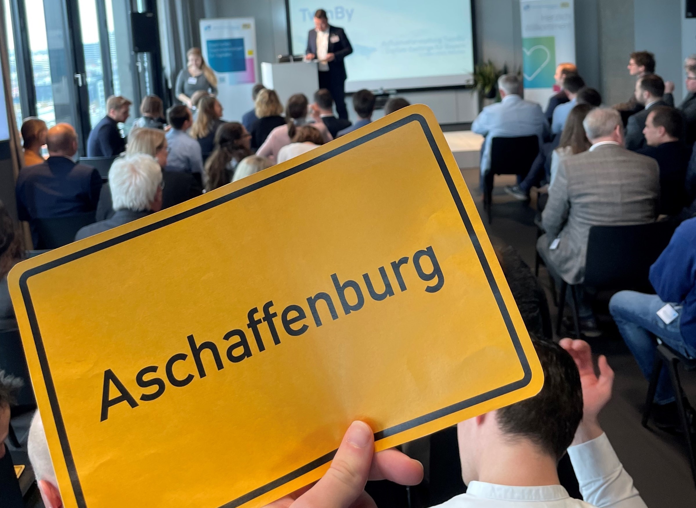 Auftaktveranstaltung TwinBy - Schild Aschaffenburg wird hochgehalten